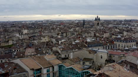 rooftops showing cailhau city gate at the french city of bordeaux while pigeon fly by, aerial pedestal rising shot