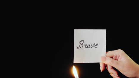 man burns a paper with the inscription brave