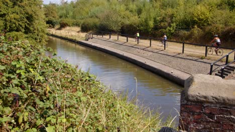 toma amplia desde aston lock mirando hacia abajo a trent y mersey canal con 3 ciclistas famley recorriendo la toma en bicicleta