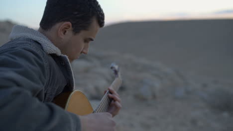 Músico-Tocando-La-Guitarra-Durante-Una-Puesta-De-Sol-En-El-Desierto