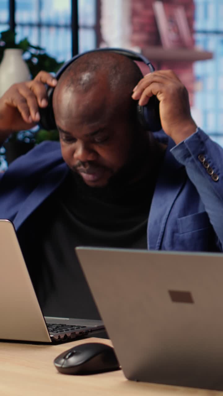 African American Man Working on Laptop and Putting on Headphones