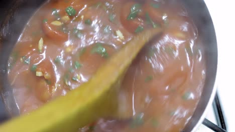 close up over head view of delicious gourmet home made tomato sauce in a hot pot with the steam rising from the boiling food while being stirred