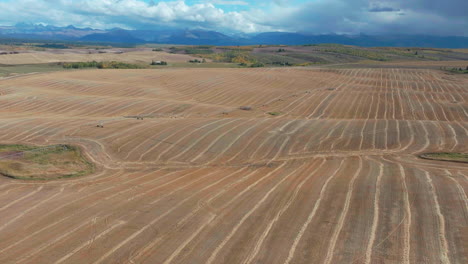 Cinematográfico-Zumbido-Aéreo-Paso-Grand-Targhee-Idaho-Parque-Nacional-Grand-Tetons-Papa-Trigo-Tierras-De-Cultivo-Seco-Cultivos-únicos-Pico-De-La-Montaña-Paisaje-Movimiento-Hacia-Atrás