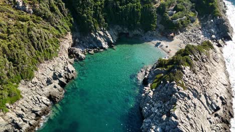 a secluded beach surrounded by cliffs and turquoise water, aerial view