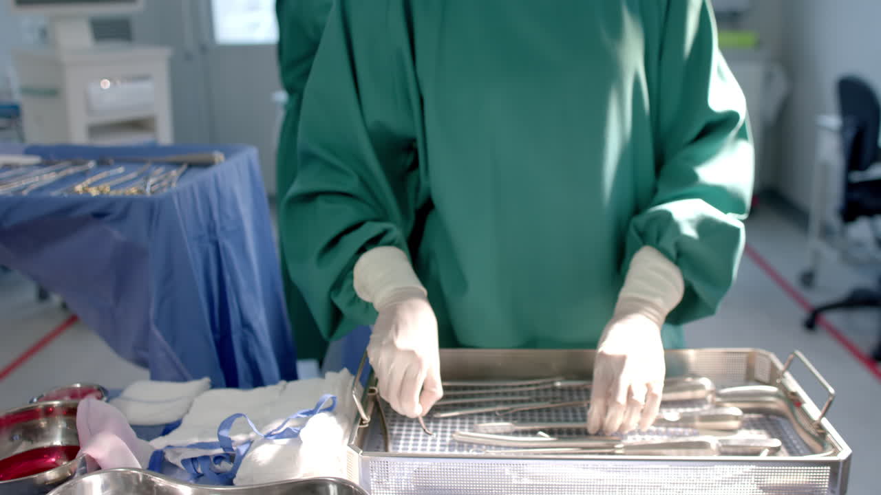 Portrait of biracial female surgeon sorting surgical tools in theatre, copy space, slow motion
