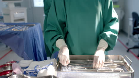 portrait of biracial female surgeon sorting surgical tools in theatre, copy space, slow motion