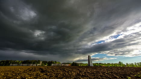 Overcast-Over-Rural-Field-In-Priekuli,-Latvia-With-Old-Water-Tower-In-Distance