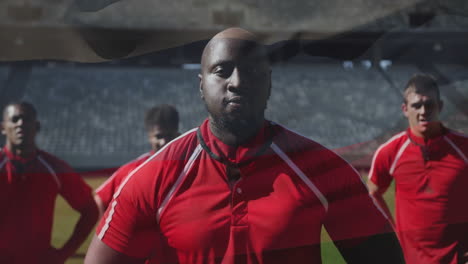 in stadium, rugby players wearing red jerseys standing confidently on field