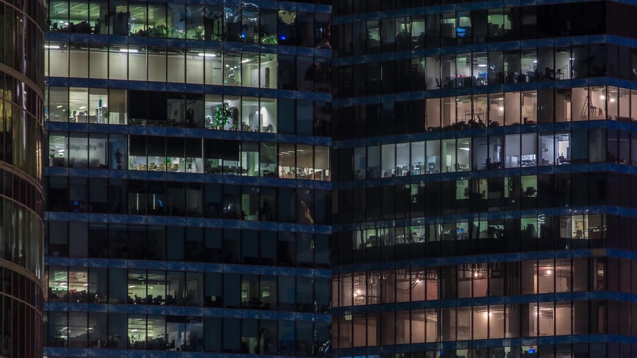 Vista ravvicinata delle finestre illuminate degli uffici nei grattacieli del Centro Affari Internazionale della Città di notte, timelapse dall'alto.