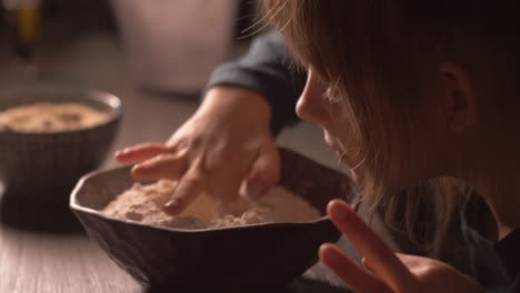 little girl blowing bowl full of baking flour mix, then making a hole in middle