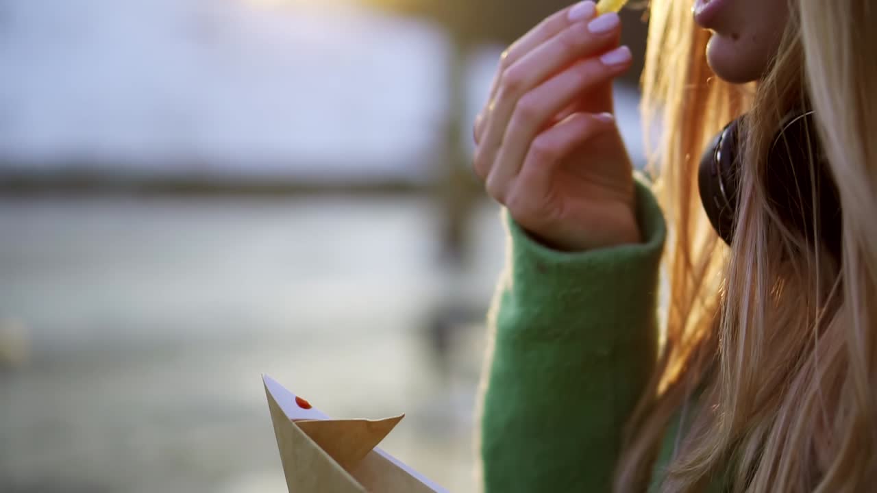 mujer comiendo papas fritas al aire libre en la calle de invierno bañada en ketchup, primer plano