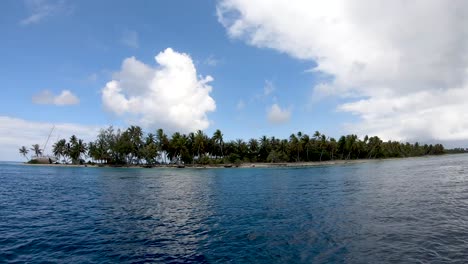 Boatride,-boat-drives-by-a-tropical-island-with-a-wrecked-sailboat-and-coconut-palm-trees-on-the-beach