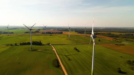 Toma-Aérea-De-Las-Turbinas-Eólicas-Que-Funcionan-En-Un-Parque-Eólico-Que-Genera-Energía-Eléctrica-Verde-En-Un-Amplio-Campo-Verde-En-Un-Día-Soleado,-Uso-De-Recursos-Renovables-De-Energía