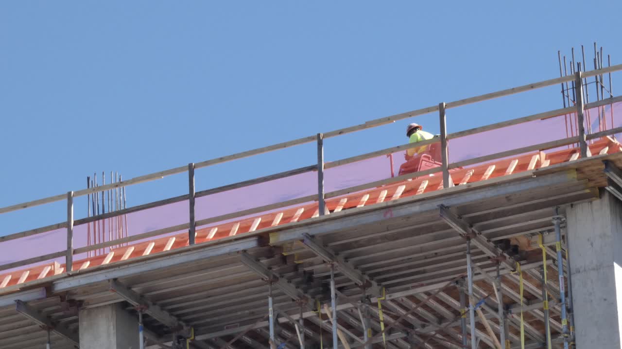 hombre en la máquina trabajando en la parte superior del edificio que se está construyendo en el sitio de construcción