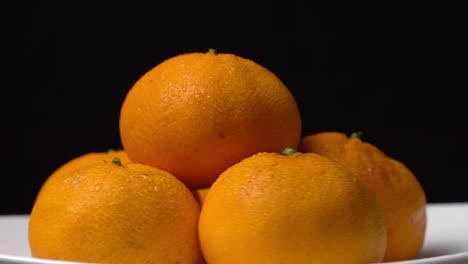 primer plano de mandarinas girando en un tocadiscos en un plato sobre un fondo negro