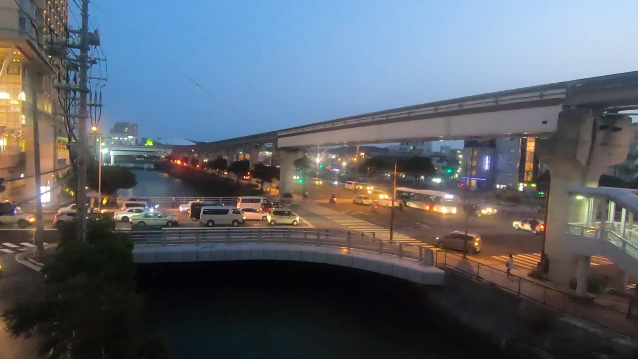 Timelapse. Naha City intersection in evening peak hour traffic. Trains travel along monorail line.