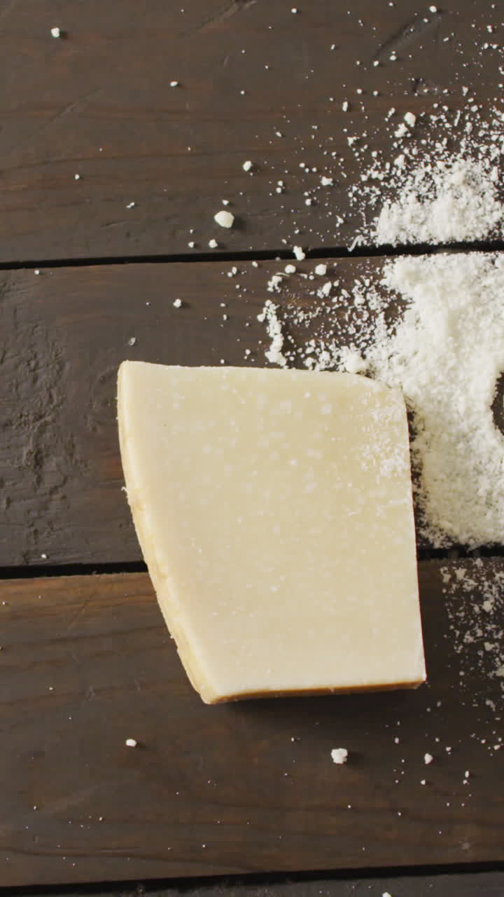 Video of block of hard cheese and heart drawn in grated cheese on rustic table with copy space
