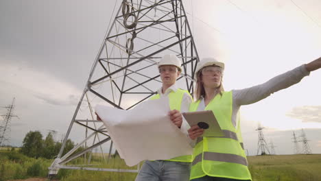 Ingeniero-Y-Supervisor-Con-Tableta-Y-Los-Dibujos-Tratan-Sobre-Líneas-Y-Torres-De-Transmisión-Y-Discuten-El-Plan-De-Expansión-Y-La-Energía-De-Transporte-Para-Pueblos-Y-Ciudades.