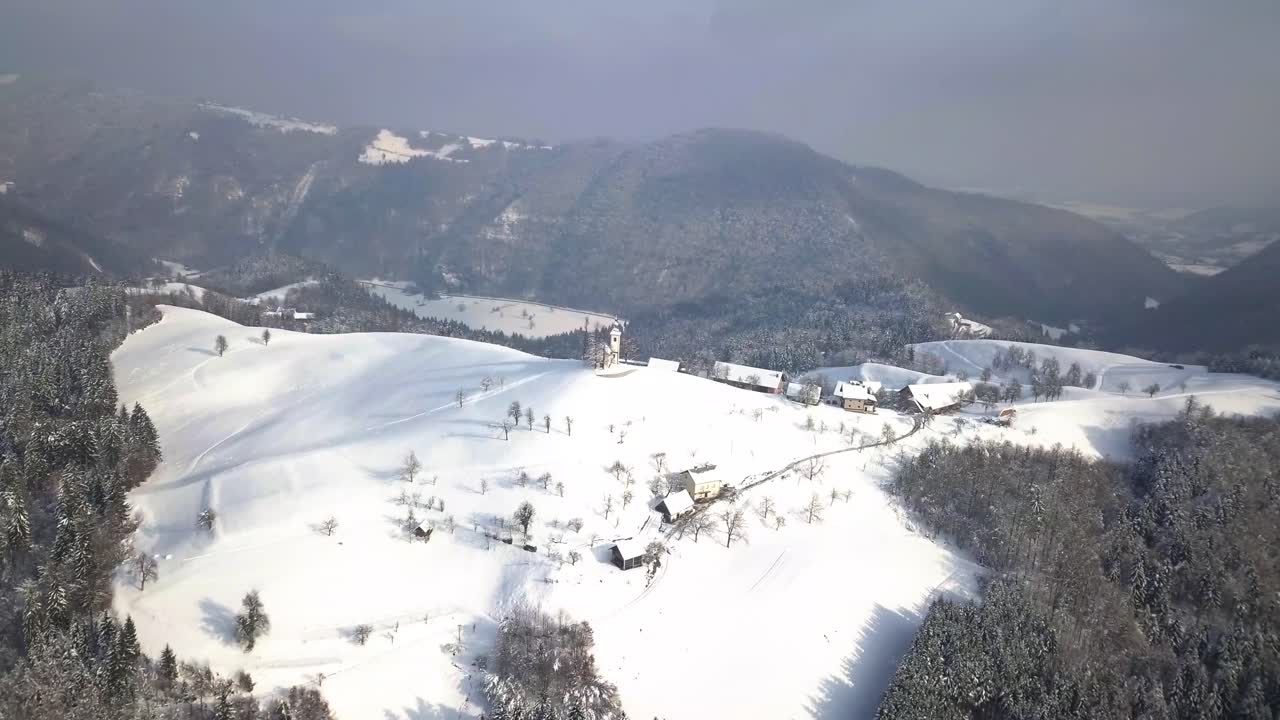겨울 동안 중앙 슬로베니아의 언덕 꼭대기에 있는 그림 같은 스베티 토마즈 교회