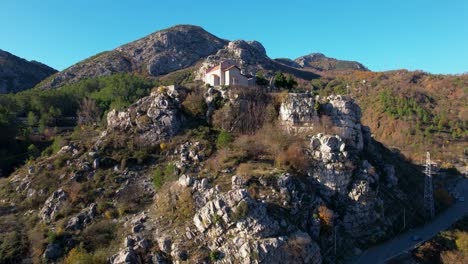 holy church and ancient monastery perched on a towering rock in rubik, albania, framed by majestic mountains