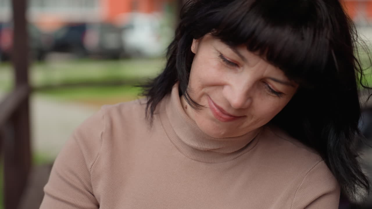 Grey Cat On Bench With Caucasian Woman Massaging Chin, CloseUp Hands With Red Nails Checking Collar And Fur, Relaxed Feline Responding With Purr, Urban Park Background, Calm Interaction