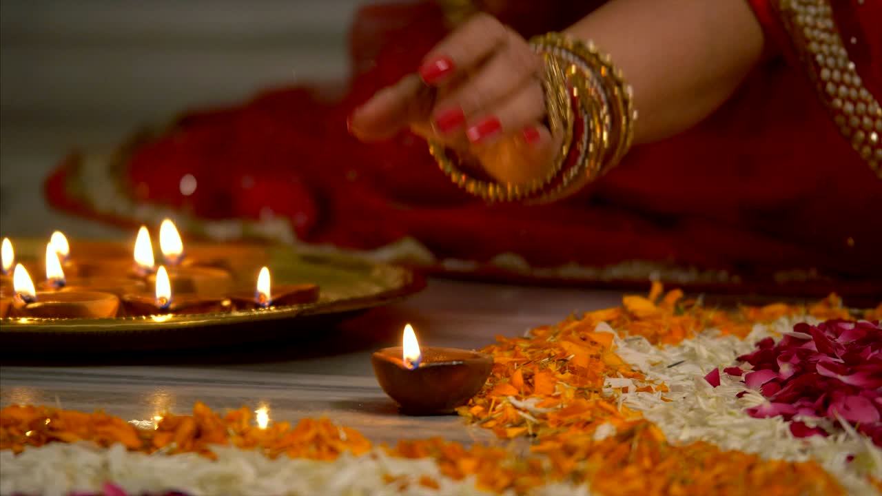 Diwali Decoration - Indian women in colourful saree and bangles decorating her house with diyas