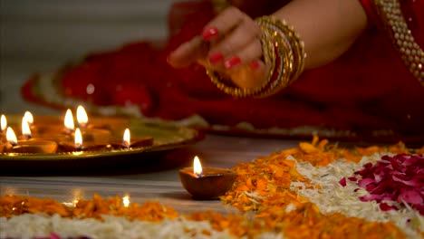 diwali decoration - indian women in colourful saree and bangles decorating her house with diyas