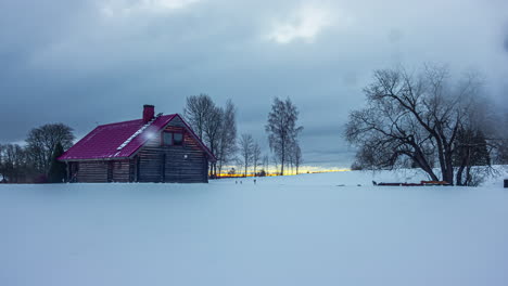 Timelapse-of-a-snowy-landscape-with-a-wooden-house-in-a-frozen-field-over-which-clouds-pass-at-high-speed-due-to-the-passage-of-time