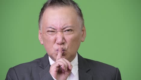 mature angry japanese businessman with finger on lips