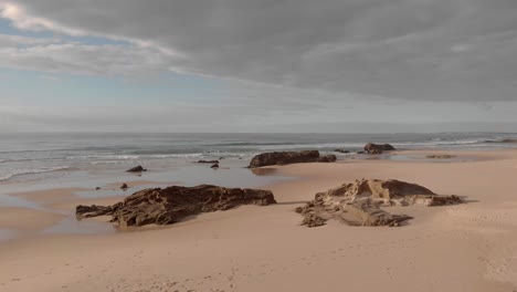 Rocky-outcrops-on-pristine-sandy-beach-backed-by-coastal-cliffs