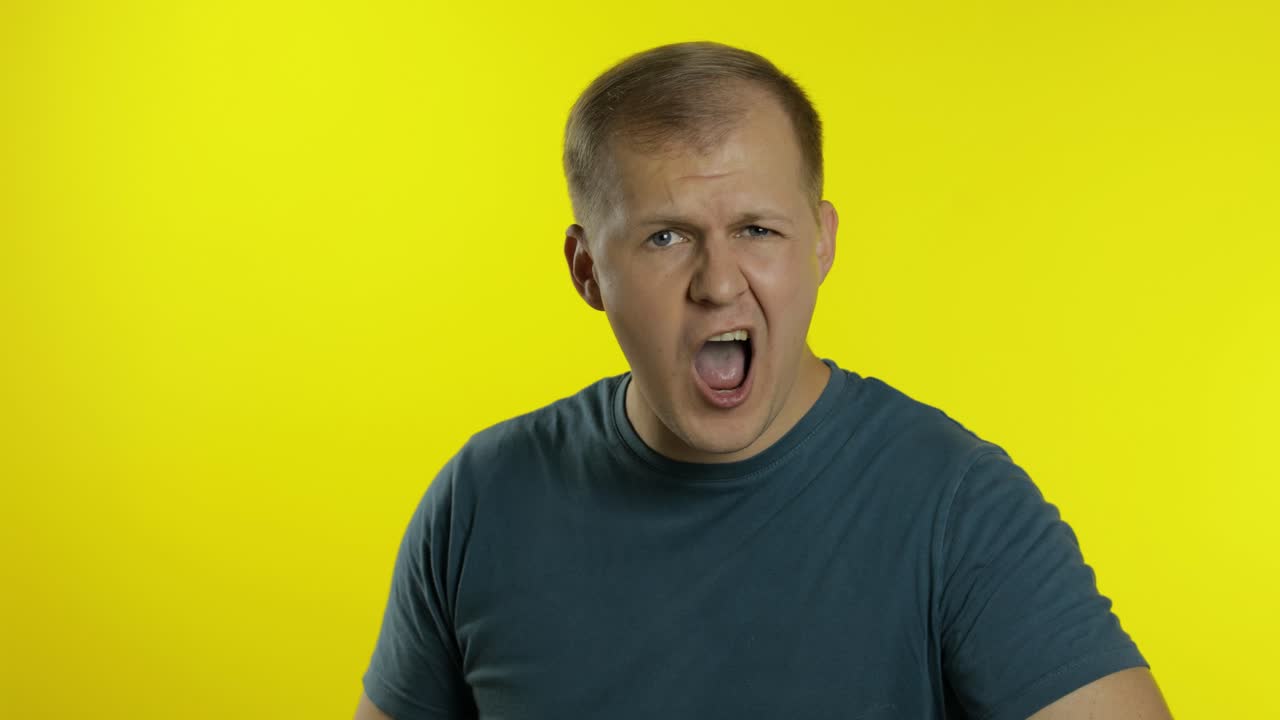 retrato de un joven caucásico posando con una camiseta verde. insatisfecho, chico exigente mirando a la cámara