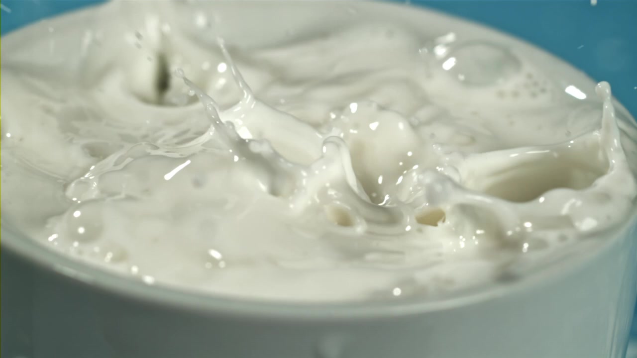 Slowmotion: Mælkedråber plasker ned i en hvid kop