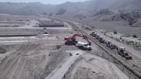 un avión no tripulado gira sobre maquinaria de construcción pesada estacionada fuera de un sitio de construcción de la casa, listo y listo para comenzar el trabajo