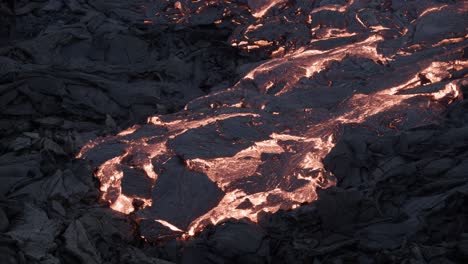 粘稠な溶岩が黒い岩の表面をゆっくりと移動し、地殻が固まっている