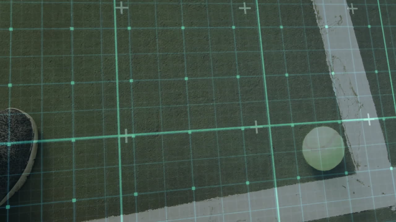 Lime-green tennis ball resting near white boundary line on green court with turquoise grid overlay