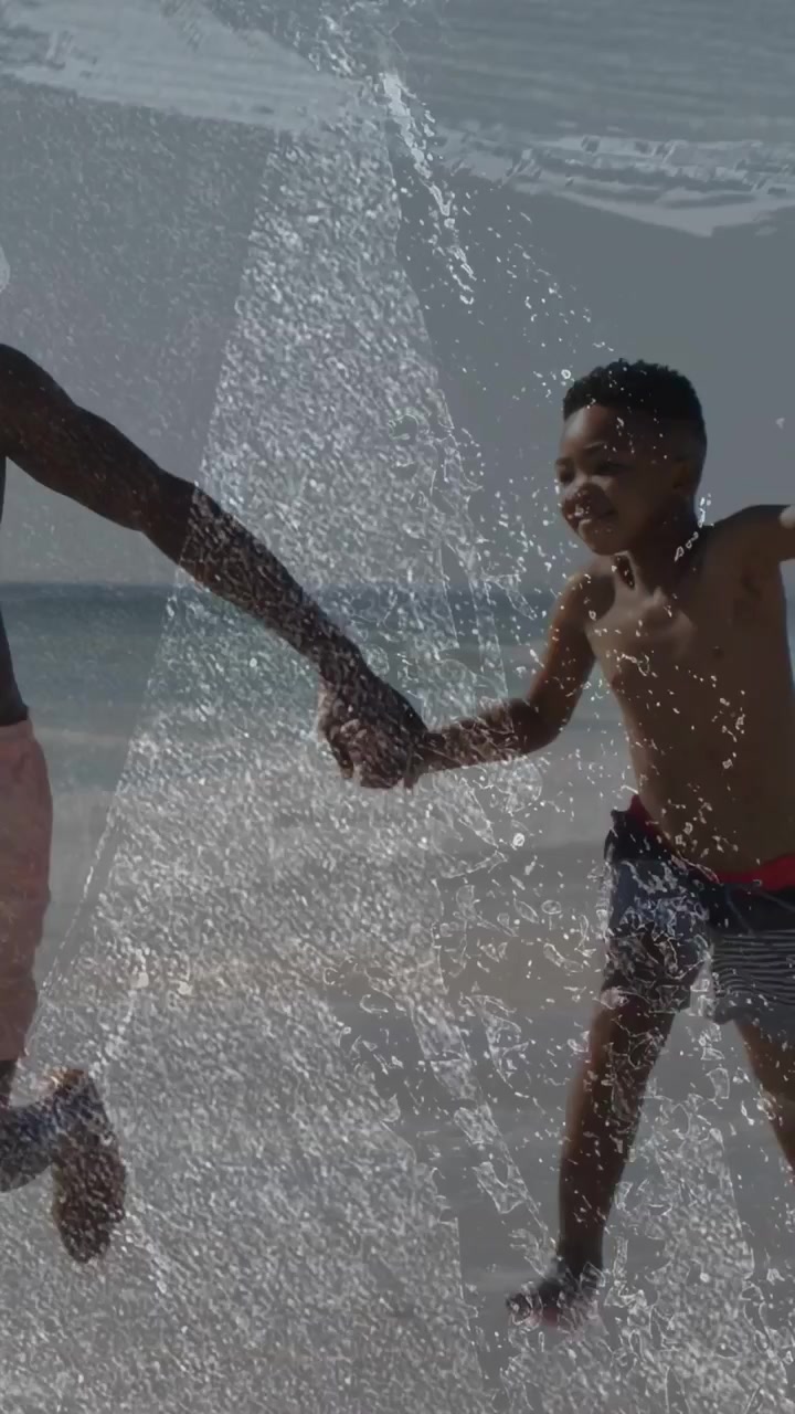 Video vertical: Hombre adulto y niño tomados de la mano, corriendo y salpicando por la playa para la salud.