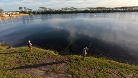 person fishing by a calm lake at dusk