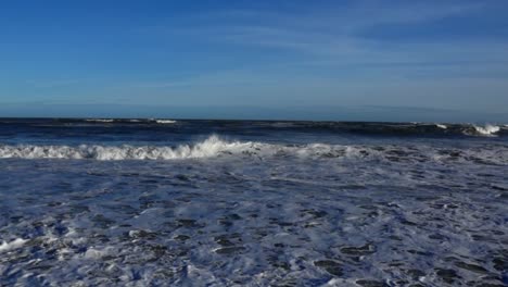 a vibrant shade of blue sky, and the ocean waves begin to build, slowly at first but steadily growing in intensity until they are crashing onto the shore in a spectacular display of power and beauty