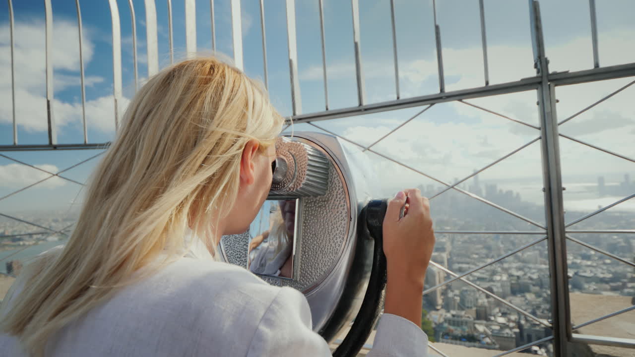 una mujer mira una hermosa vista de nueva york desde la plataforma de observación el viento juega con su cabello