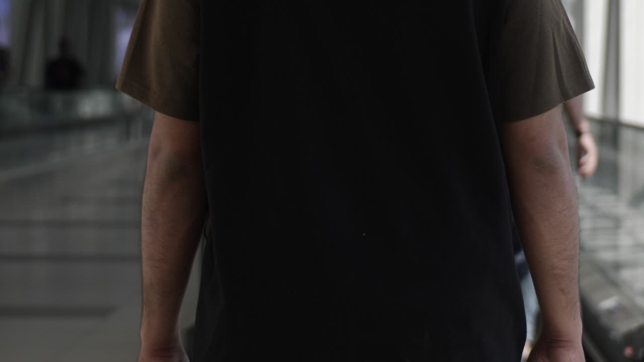 hombre vestido con camiseta caminando en cámara lenta mientras está de compras en el centro comercial dubai en los emiratos árabes unidos