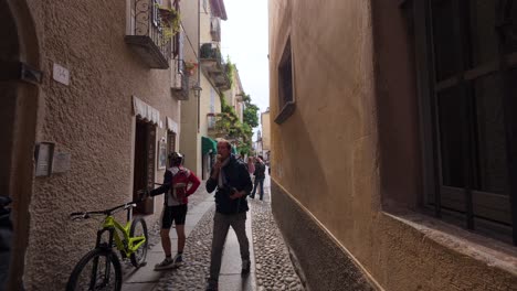 tourists walking along a quaint cobblestone street in san giulio, italy, surrounded by historical architecture and vibrant atmosphere.