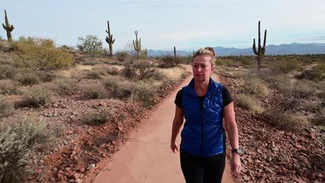 Mujer-Caminando-Por-Un-Sendero-Pavimentado-En-Un-Paisaje-Desértico