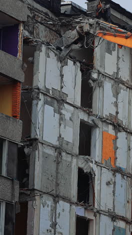 top floors destruction by the hydraulic claw of excavator. demolition of old house building for new construction by excavator bucket. view from the below. vertical video