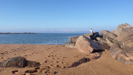 Typ,-Der-An-Einem-Felsigen-Strand-Auf-Den-Horizont-Starrt