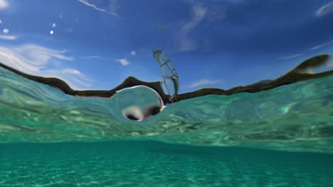 medio punto de vista bajo el agua de una surfista que se divierte navegando con una tabla de surf en la superficie del agua del mar
