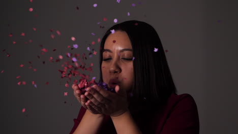 Young-woman-blows-confetti-from-her-palms-and-throws-the-rest-over-her-head---Slow-motion
