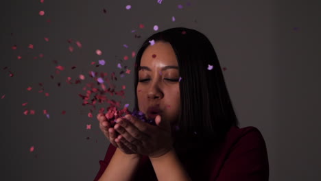 young woman blows confetti from her palms and throws the rest over her head - slow motion