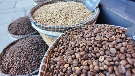 close-up of baskets filled with different types of coffee beans, including roasted, green, and ground coffee, with a 'romeo coffee' sign visible