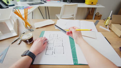 pov shot of architect putting on glasses working in office measuring plans for new building