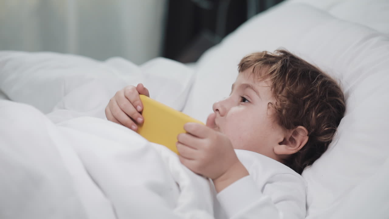 A child using a phone in bed